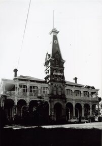 A photograph of a two storey Victorian mansion with a decorative tower over the main entrance.