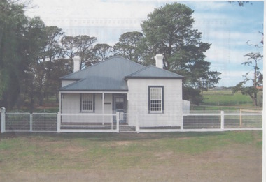 A small double fronted wooden cottage with a corrugated iron roof with trees growing behind the building.