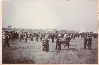 A photograph of a lot of people caught in a sudden shower of rain and running for shelter at a race meeting.