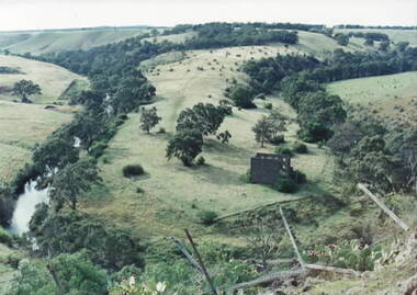 Photograph of the ruins of a bluestone mill that was built on a bend of a river.