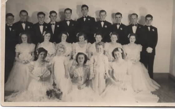 Ten debutantes and their partners along with the flower girl and page boy are posing for their photograph.