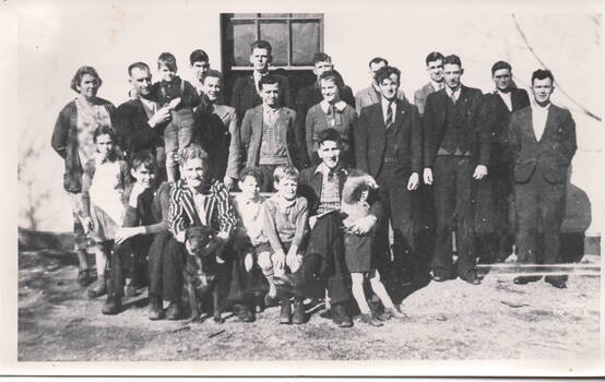 Twenty two people and a dog standing and sitting outside a hotel in Sunbury.