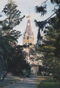 A picture of garden and a Victorian mansion with a tall tower over the main entrance.