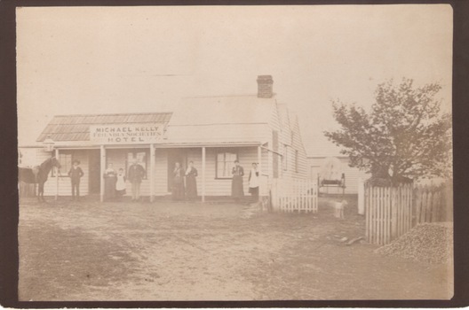 A single storey hotel building with seven people standing in the front of the building.