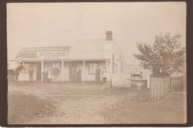 A single storey hotel building with seven people standing in the front of the building.