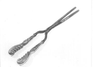 Metal tongs for curling hair with ornately carved handles.