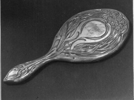 Ornately embossed sterling silver backed hand mirror with handle.