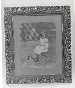Large photograph of girl on child's bicycle.