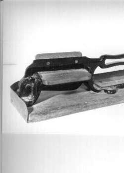 Black metal guillotine type slicer for cutting tobacco from plug.