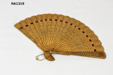 Carved wooden fan with purple ribbon thread.