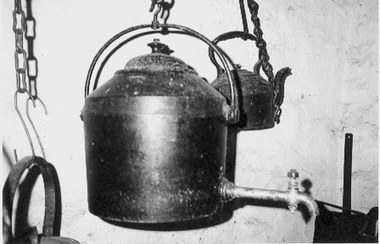 Enormous black cast iron kettle with lid.