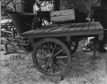 Flat tray,(wooden) two wheeled vehicle with spreader mounted at rear.