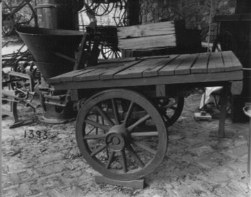 Flat tray,(wooden) two wheeled vehicle with spreader mounted at rear.