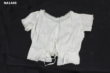 White cotton camisole with blue ribbon threaded through eyelets at neck. Lace border on neck, sleeves and front. 