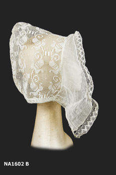 Side view of cap of stiffened machined lace with two pleated 'wings' of stiffened and pleated chiffon on either side.  