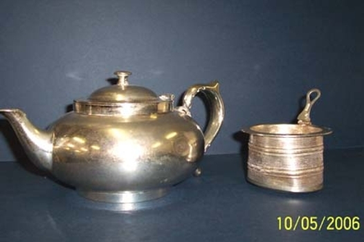 A round squat silverplated Robur teapot containing a fitted round cup shaped strainer with hinged pull for removal.