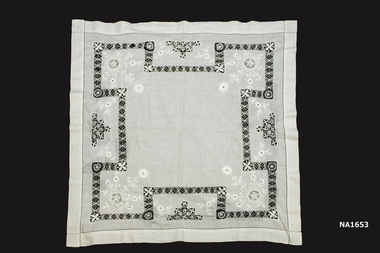 White cotton supper cloth with white embroidered with a wide band of drawthread with needle embroidery at corners. Embroidery has raise pattern,