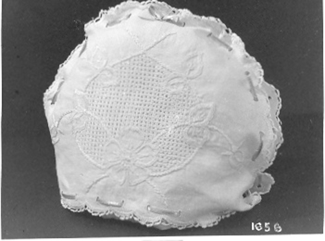 White cotton tea cover with pulled thread embroidered surrounded by button hole embroidery. 