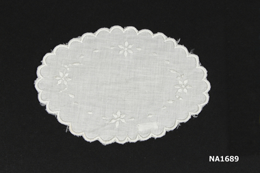 Oval shaped white cotton doyley embroidered in white.