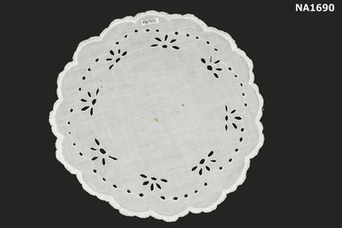 Round white cotton doyley decorated with cut out embroidery.