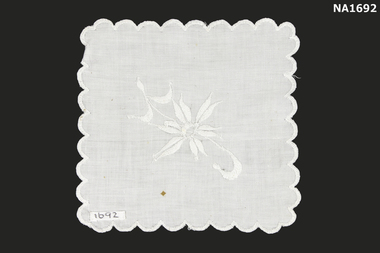 Square white cotton doyley with centre flower embroidery in white.