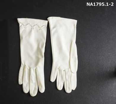 Pair  off-white wrist gloves with decoration at wrist.