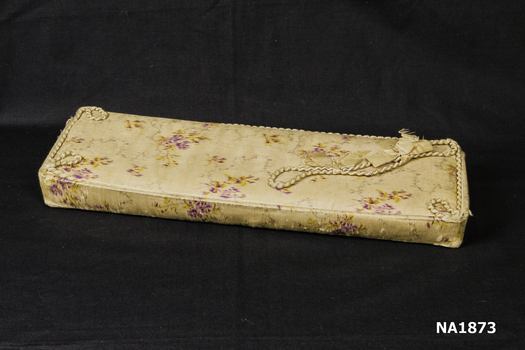 Long rectangular box covered in dark cream silk with purple pattern. 