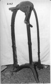 Long thin shaft standing on a three legged round base. 