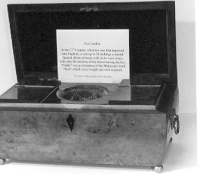 Burr walnut tea caddy with ornate brass handles and four round brass legs.