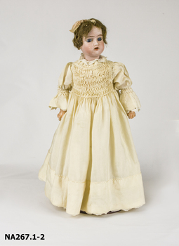 Bisque Doll dressed in cream silk smocked dress with crocheted lace border on collar.and hem. 