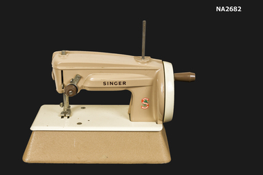 Toy Singer sewing machine - cast metal and plastic with needle and operating mechanism. Hand operated. Finished in dark beige.