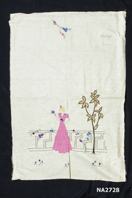 Cream calico apron embroidered with a lady in pink gown with a palm tree and flowers on fence.