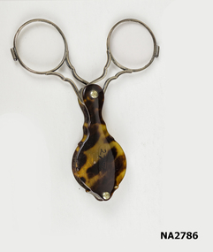 Small hand held lorgnette with two lenses set in silver chased circular frames.