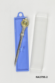 Nickel plated spear shape with round emblem inscribed with Rotary International on blue panels on cream and gold circle. Centre crossed with blue panels covered with plastic.