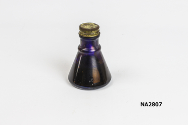 Cone shaped ink bottle made of glass, with a metal lid.