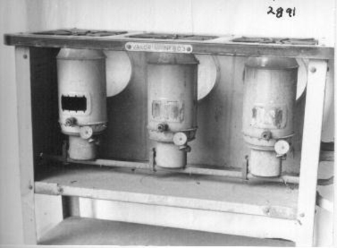 Unit consists of a base with three large adjustable kerosene burners under a grid on which pots and pans were placed.