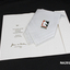 White cotton handkerchief with gold inscription folded into a white inscribed card.