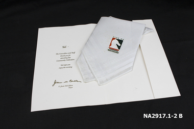 White cotton handkerchief with gold inscription folded into a white inscribed card.
