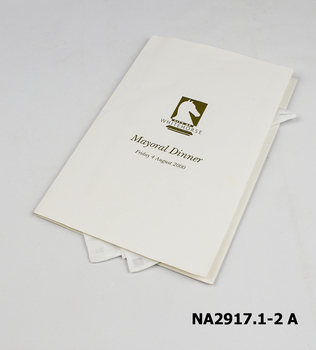 White cotton handkerchief with gold inscription folded into a white inscribed card.