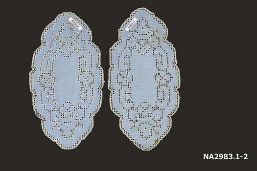 A pair of blue linen mats with white embroidery thread on drawn thread work with scalloped edge.