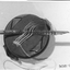 Round wooden block with sample of material to demonstrate how to use the darner and needles.