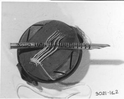 Round wooden block with sample of material to demonstrate how to use the darner and needles.