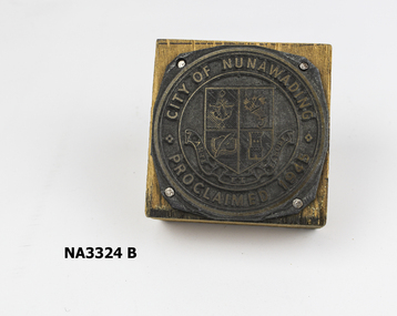 Square wooden block on which round metal plate nailed; 