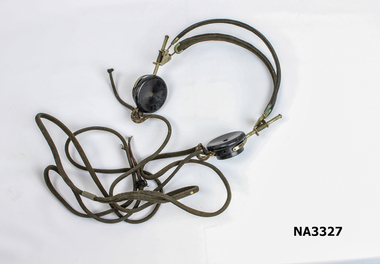  Two black bakelite earphones connected to metal hinges and two cloth band head rests. 