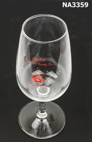 Wine glass with inscription in red of white horse on building. 