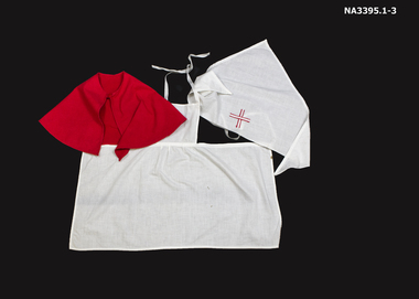 Child's nurse outfit consisting of white apron, red cape and triangular headdress/veil with stitched red cross.