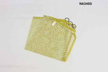 A square of plastic 'lace' decorated with yellow ric-rac