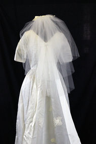 White tulle veil attached to comb with cream satin bow sewn on to it. 