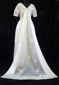 1963 Wedding dress of cream satin; floor length, short sleeves, round neckline (back)