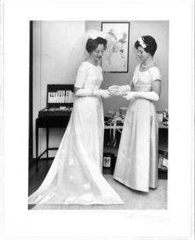 1963 Wedding dress of cream satin; floor length, short sleeves, round neckline, fitted at waist.